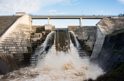 Full weir flowing with water while viewing platform above allows people to pass overhead. - Australian Stock Image