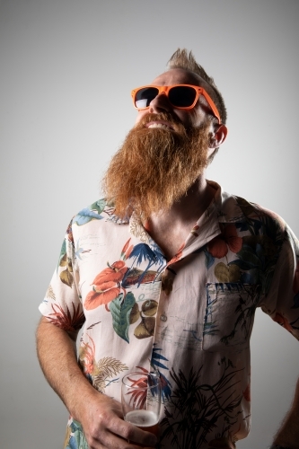 Funky man posing for photographs, holding a glass of beer - Australian Stock Image