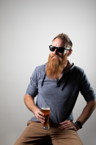 Funky man posing for photographs, holding a glass of beer - Australian Stock Image