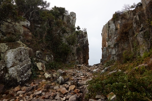 Gap in coastal rocky headland landscape on overcast morning - Australian Stock Image