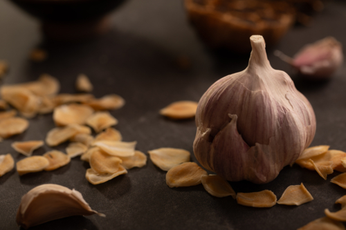 Garlic bulb and garlic chips on dark benchtop - Australian Stock Image