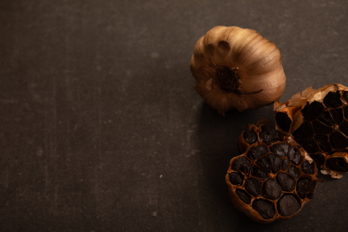 Garlic bulb sliced in half showing cloves on dark benchtop - Australian Stock Image