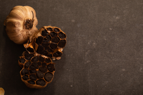 Garlic bulb sliced in half showing cloves on dark benchtop - Australian Stock Image