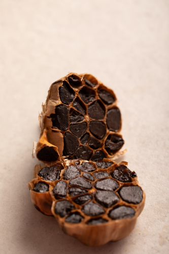 Garlic bulb sliced in half showing cloves on light benchtop - Australian Stock Image
