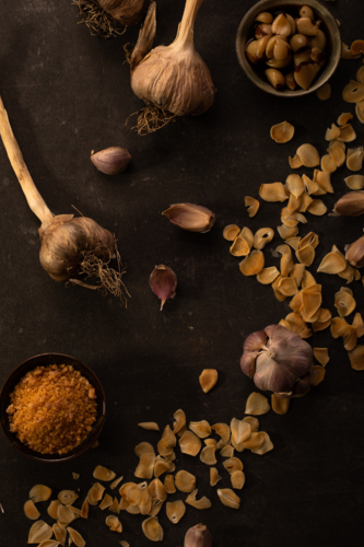 Garlic cloves and chips on dark surface - Australian Stock Image