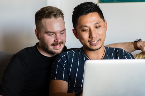 Gay couple on sofa with laptop - Australian Stock Image