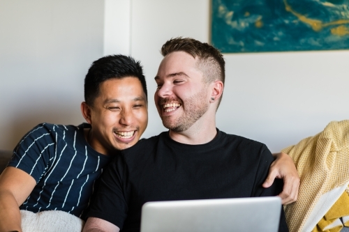 Gay couple on sofa with laptop - Australian Stock Image
