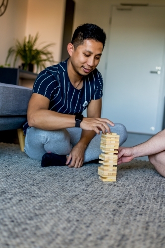 Gay couple playing fun block game at home - Australian Stock Image