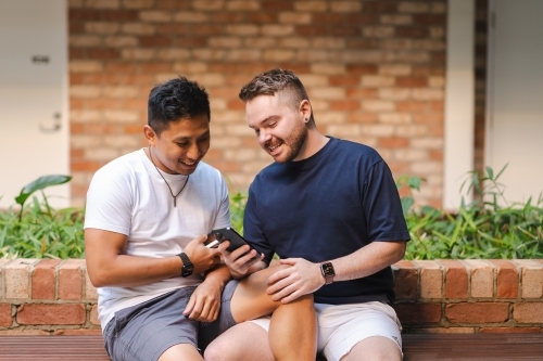 Gay couple sitting on a bench - Australian Stock Image