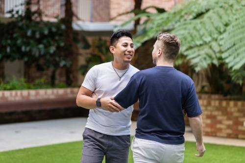Gay couple walking playfully - Australian Stock Image