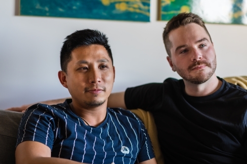 Gay male couple sitting on couch - Australian Stock Image