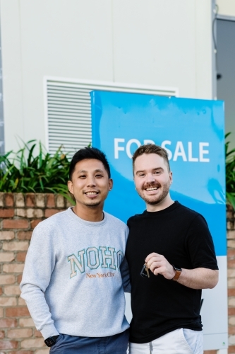gay men in front of for sale sign - Australian Stock Image