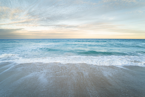 Gentle ocean tide washing over wet sandy beach at Scarborough Beach, Perth, Western Australia - Australian Stock Image