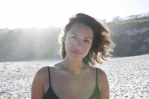 Girl at beach with sun behind her - Australian Stock Image