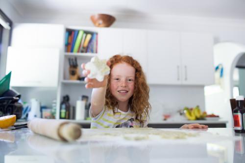 Girl baking biscuits in the kitchen - Australian Stock Image