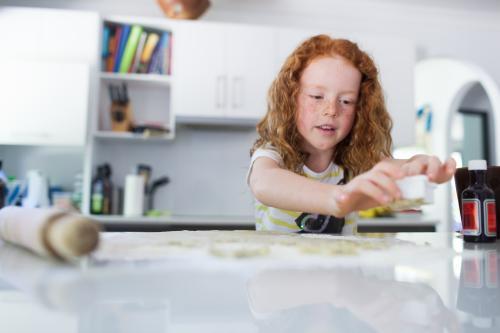Girl baking biscuits in the kitchen - Australian Stock Image