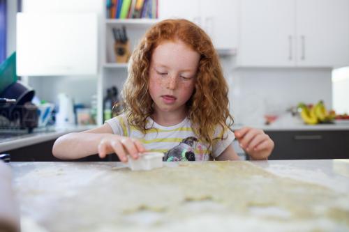 Girl baking biscuits in the kitchen - Australian Stock Image