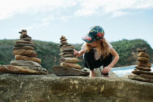 Girl balancing rocks at the beach - Australian Stock Image