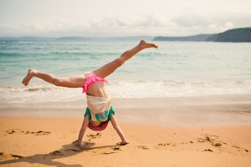 Girl cartwheeling on the beach - Australian Stock Image