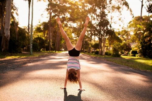 Girl doing a handstand on a road - Australian Stock Image