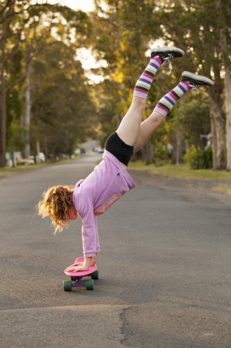 Girl doing a handstand on a skateboard - Australian Stock Image