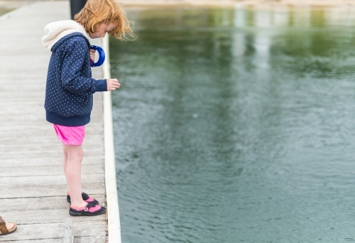 girl fishing with a hand reel from a wooden jetty - Australian Stock Image