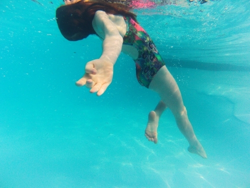 Girl floating undewater in a pool - Australian Stock Image