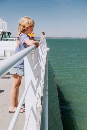 Girl gazing out to the ocean as she crosses on ferry - Australian Stock Image