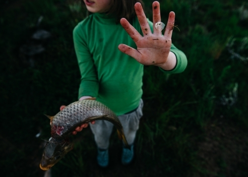 Girl holding carp showing dirty hand