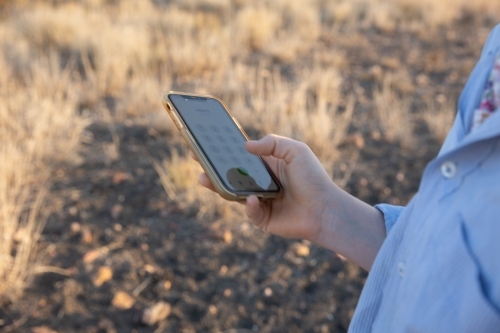 Girl holding mobile phone in paddock - Australian Stock Image