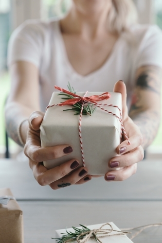 Girl holding out a gift wrapped christmas present - Australian Stock Image