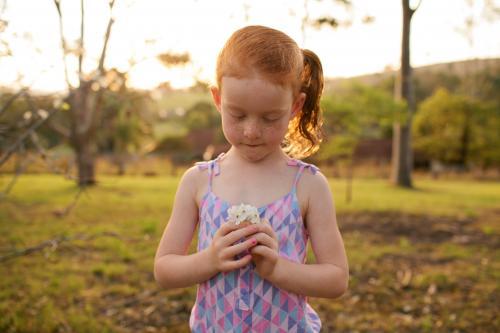 Girl in a field looking at some flowers - Australian Stock Image