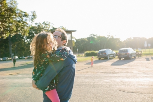 Girl in her father's arms, cranky to be leaving - Australian Stock Image