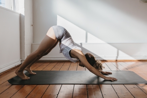 Girl in the downward dog yoga pose in a gym - Australian Stock Image