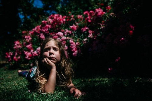 Girl laying in garden, resting her chin in her hand - Australian Stock Image