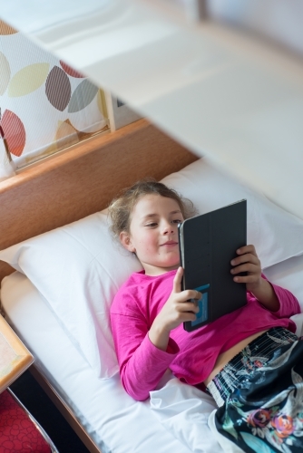 Girl laying on bunkbed looking at ipad