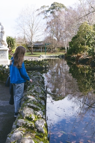 Girl looking into water reflections at Ballarat Botanic Garden - Australian Stock Image