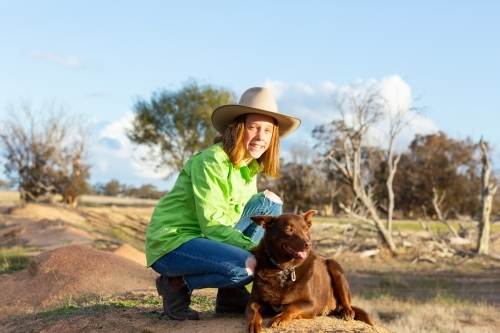 Girl on a farm with red kelpie dog