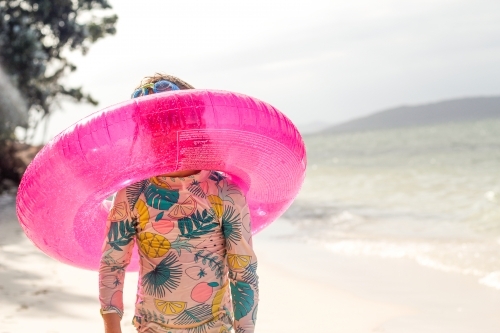 Girl on the beach with a pink swim ring