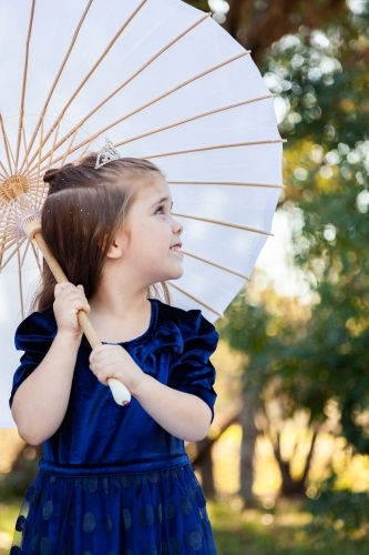 Girl playing dress ups with a parasol and tiara - Australian Stock Image