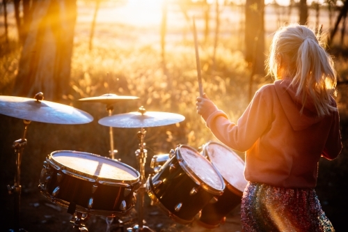 Girl playing drums outdoors in the sunshine - Australian Stock Image