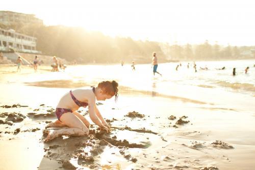 Girl playing in the sand at the beach - Australian Stock Image