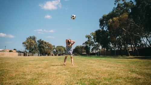 Girl playing soccer in the park with the ball in the air