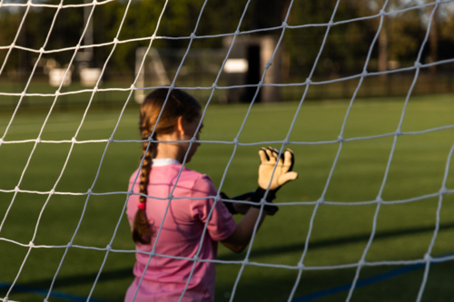 girl playing soccer putting on goalkeeper gloves - Australian Stock Image