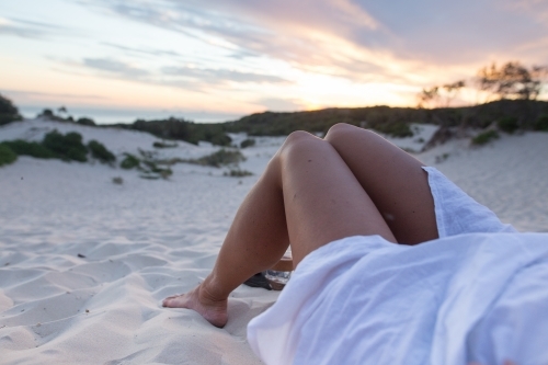 Girl relaxing at the beach watching the sunset - Australian Stock Image