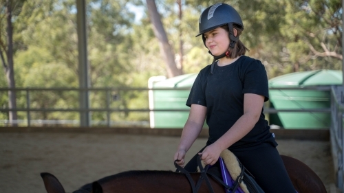 Girl riding a horse in arena - Australian Stock Image