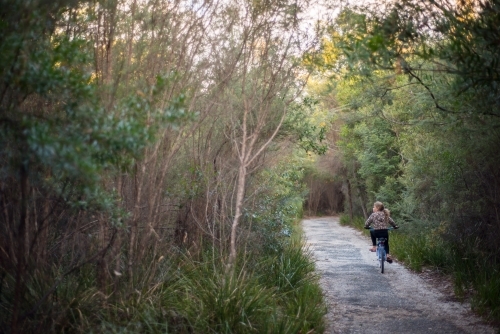 Girl riding bike along path in bush
