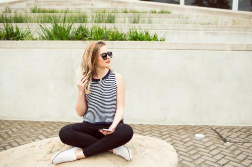 Girl sitting cross-legged wearing sunglasses - Australian Stock Image