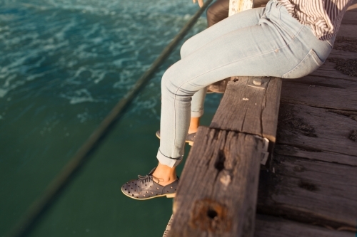 Girl sitting with legs dangling over a jetty