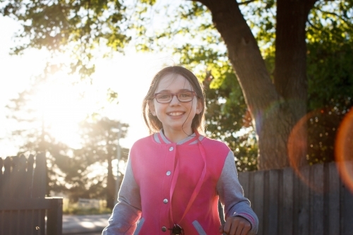 Girl smiling and walking through the wooden fence at dusk - Australian Stock Image